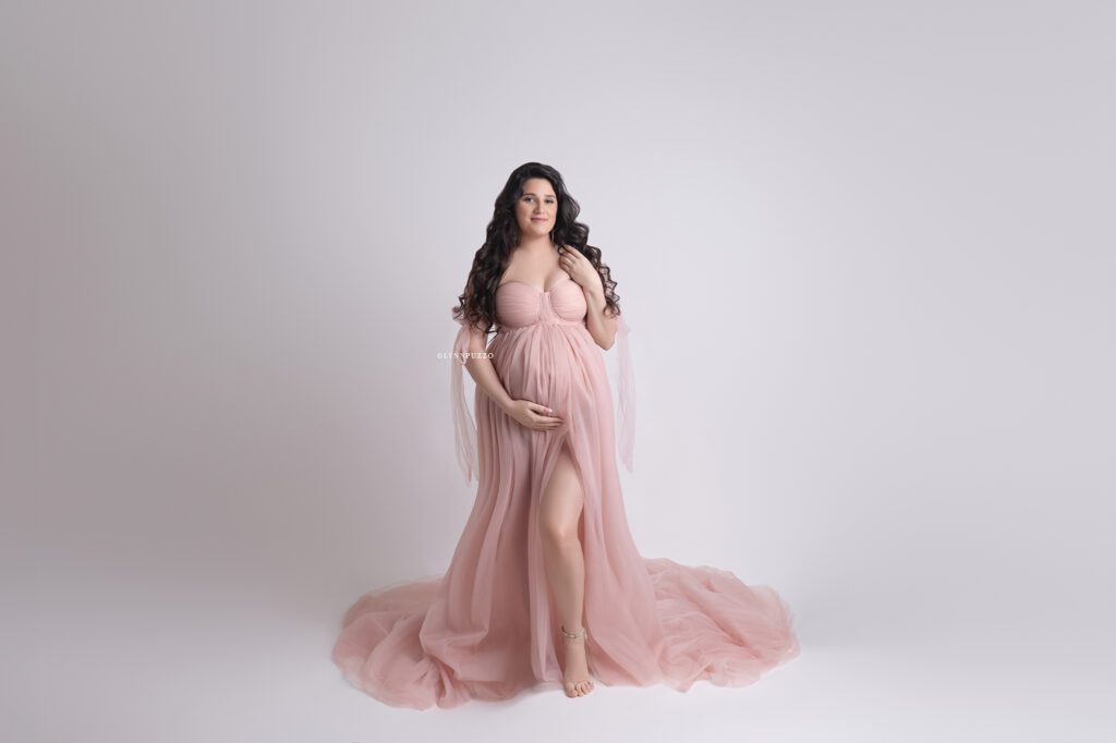 Pregnant mother in flowing blush gown with soft lighting, luxury south atlanta maternity photography studio