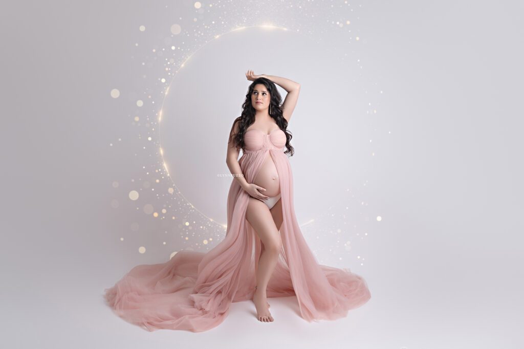 Pregnant mother in flowing blush gown with soft lighting, luxury south atlanta maternity photography studio