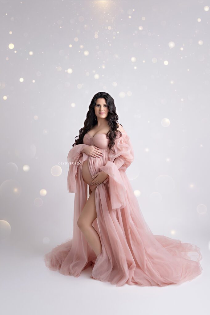 Pregnant mother in flowing blush gown with soft lighting, luxury south atlanta maternity photography studio
